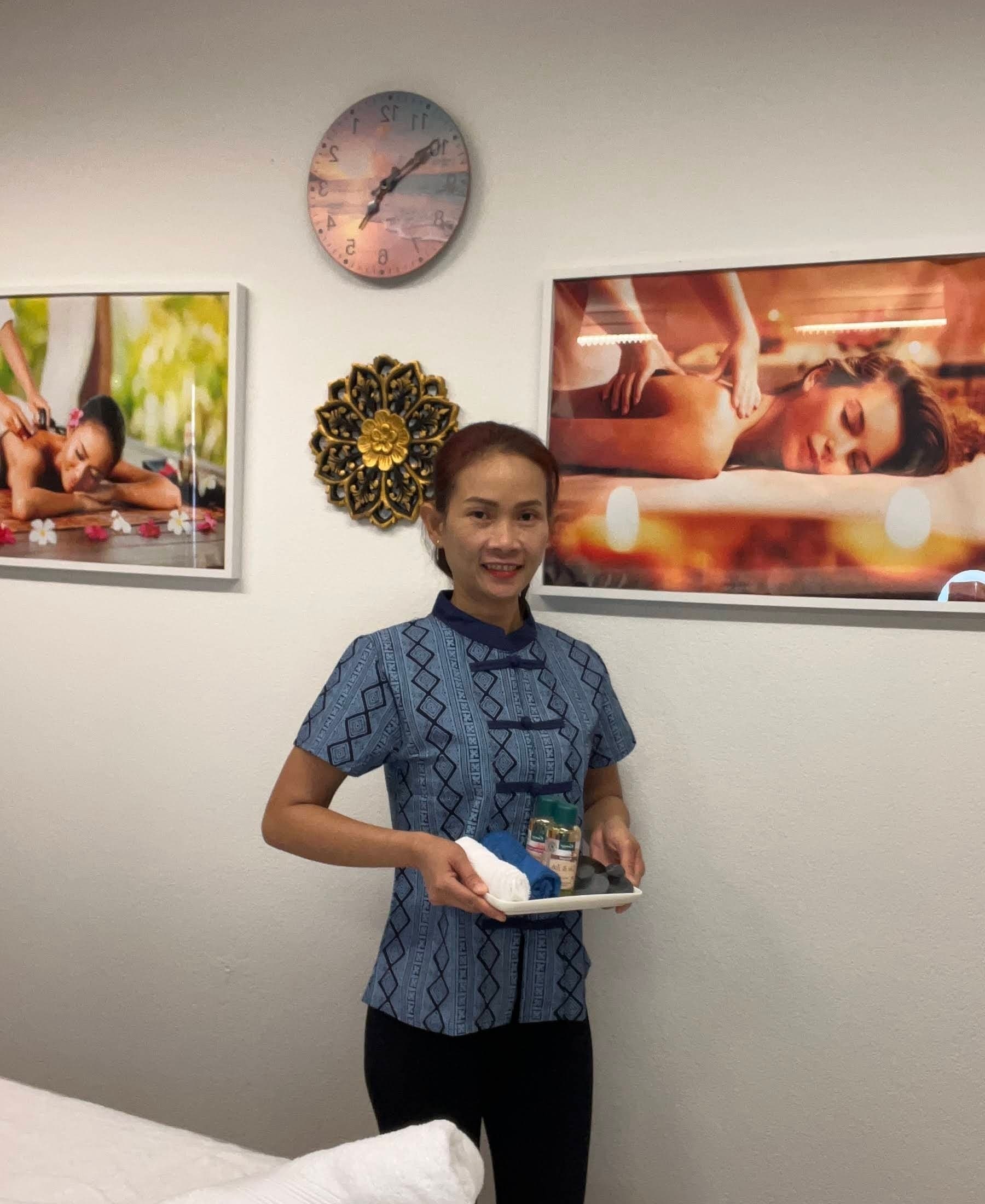 Therapeutin von Relax Spa Thai Massage Liestal mit Massage-Ölen vor Wellness-Postern
